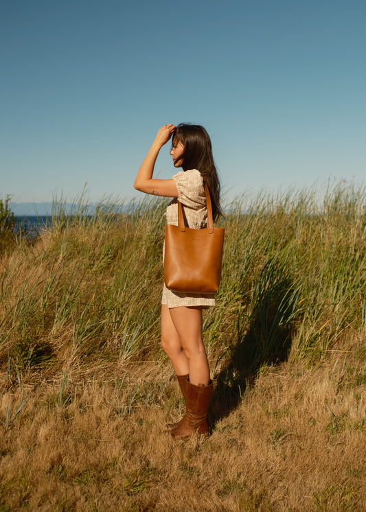 Woman standing in a field with a brown leather bag