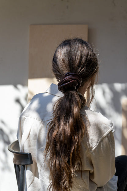 Person with long hair in a ponytail sitting outdoors.