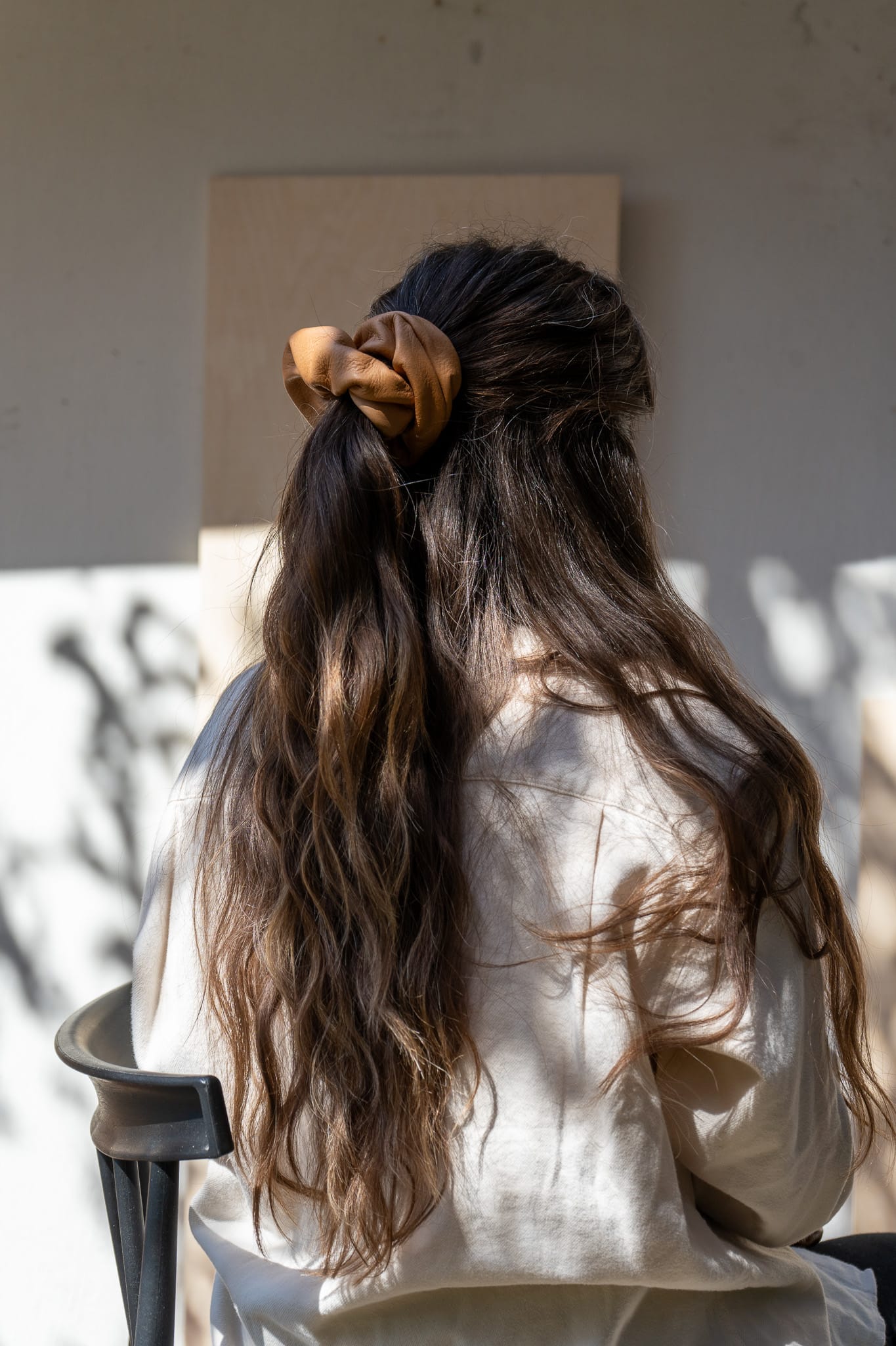 Person with long, wavy hair tied back, wearing a beige shirt.
