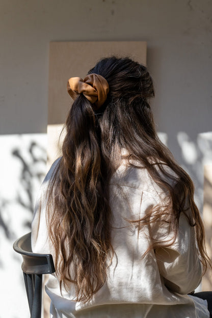 Person with long, wavy hair tied back, wearing a beige shirt.