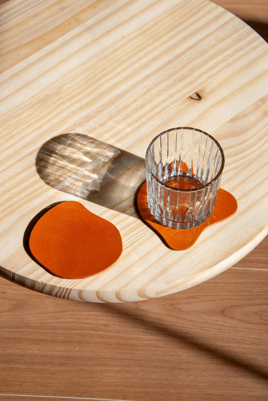 Clear glass on a tan coaster with a wooden tray on a wooden surface.