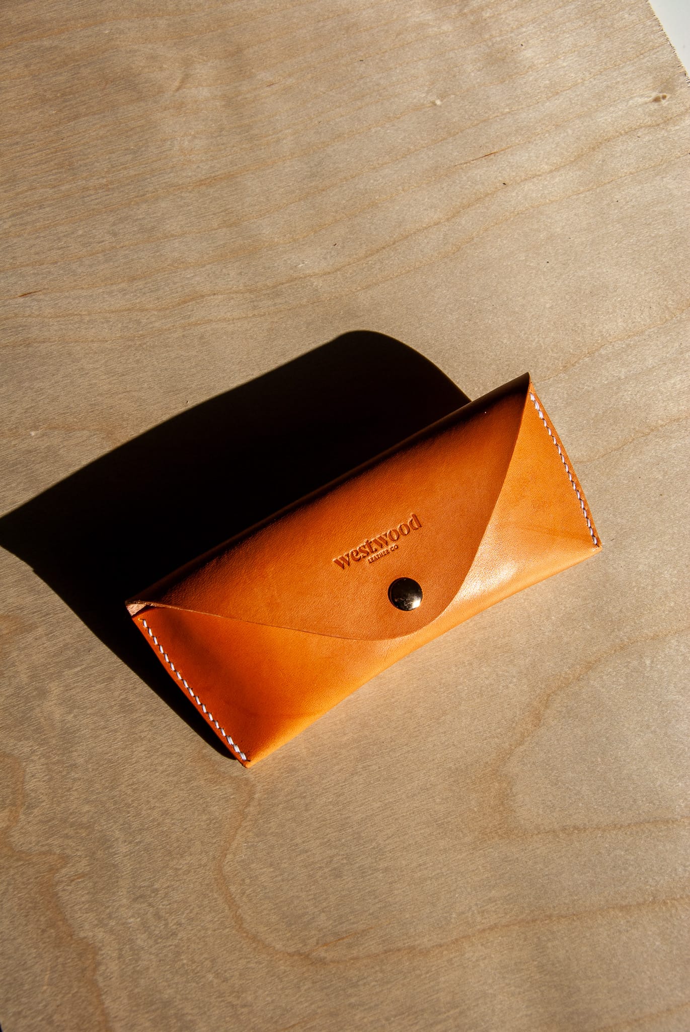 Brown leather pouch with 'Westwood' branding on a wooden surface