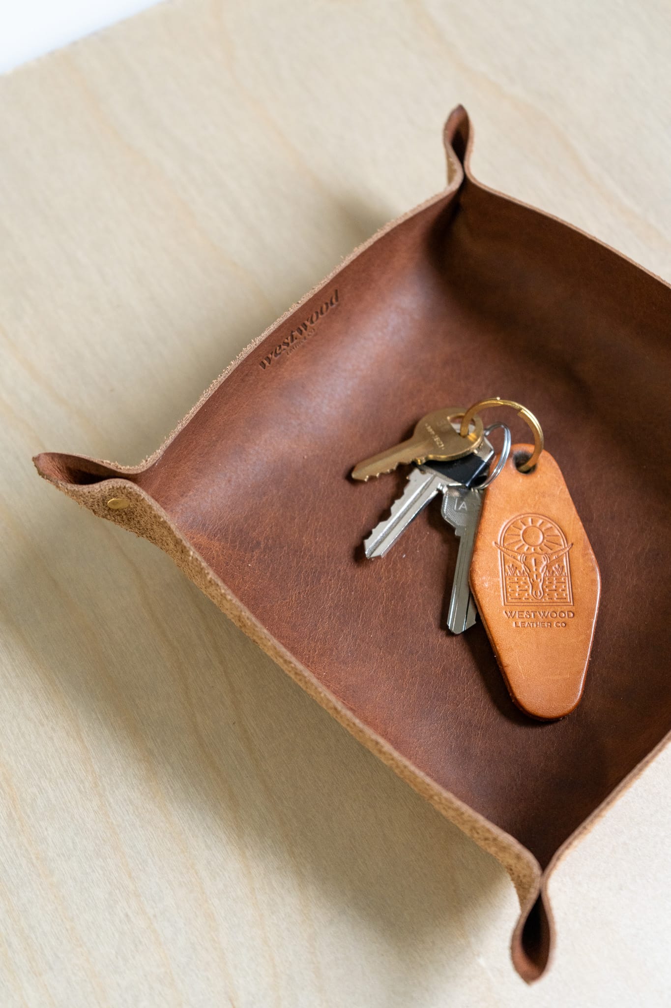 a brown leather tray holds a keychain on a wooden background