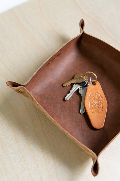 a brown leather tray holds a keychain on a wooden background