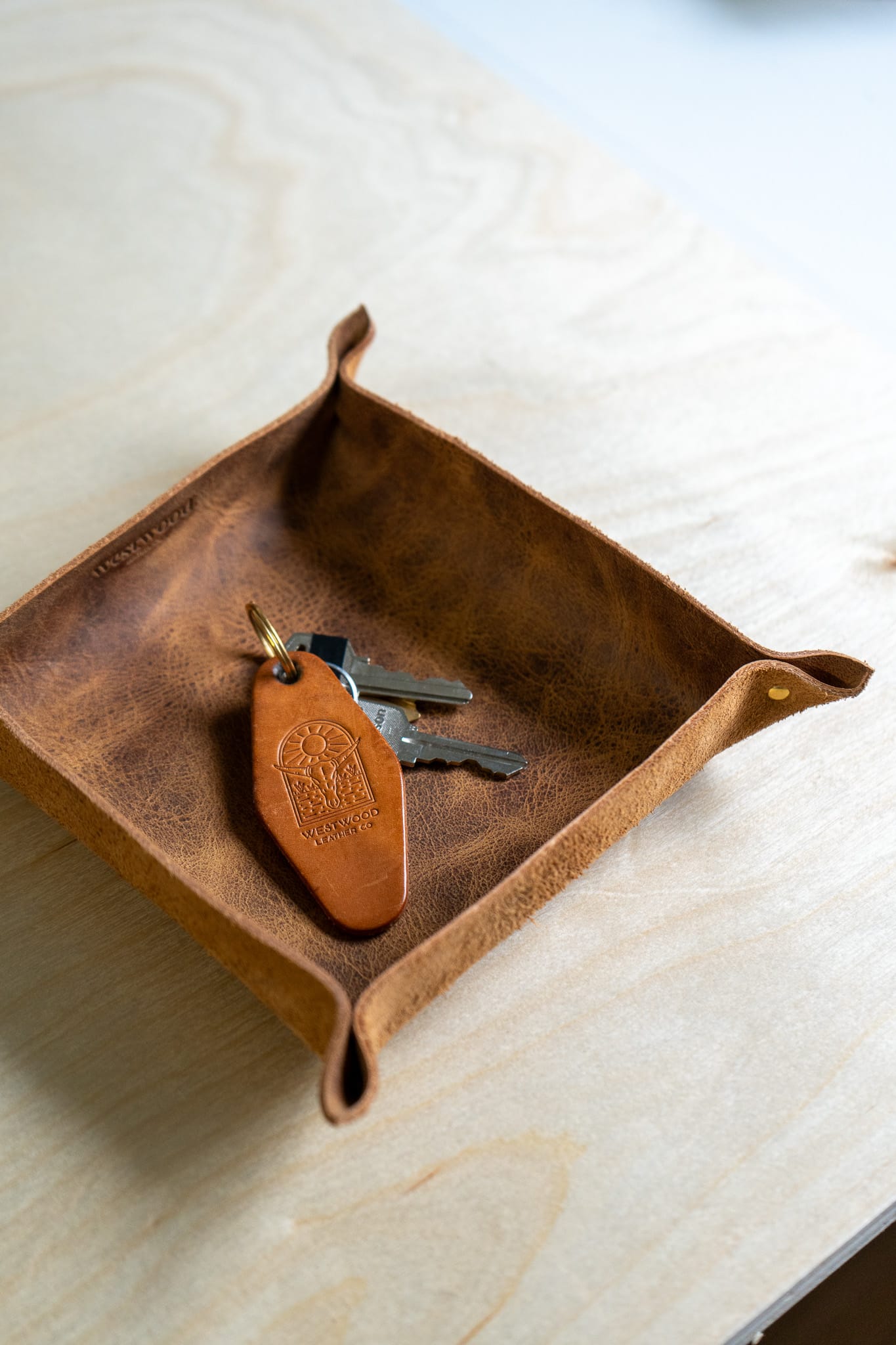a brown leather tray holds a keychain on a wooden background