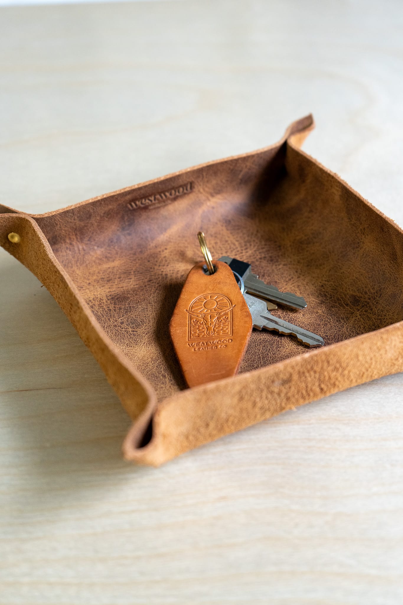 a brown leather tray holds a keychain on a wooden background