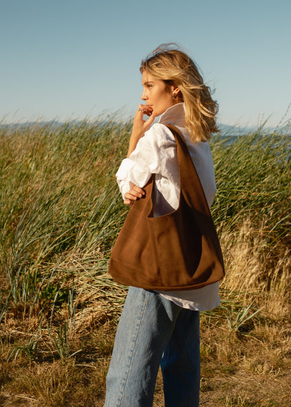 Woman holding a brown bag in a grassy field