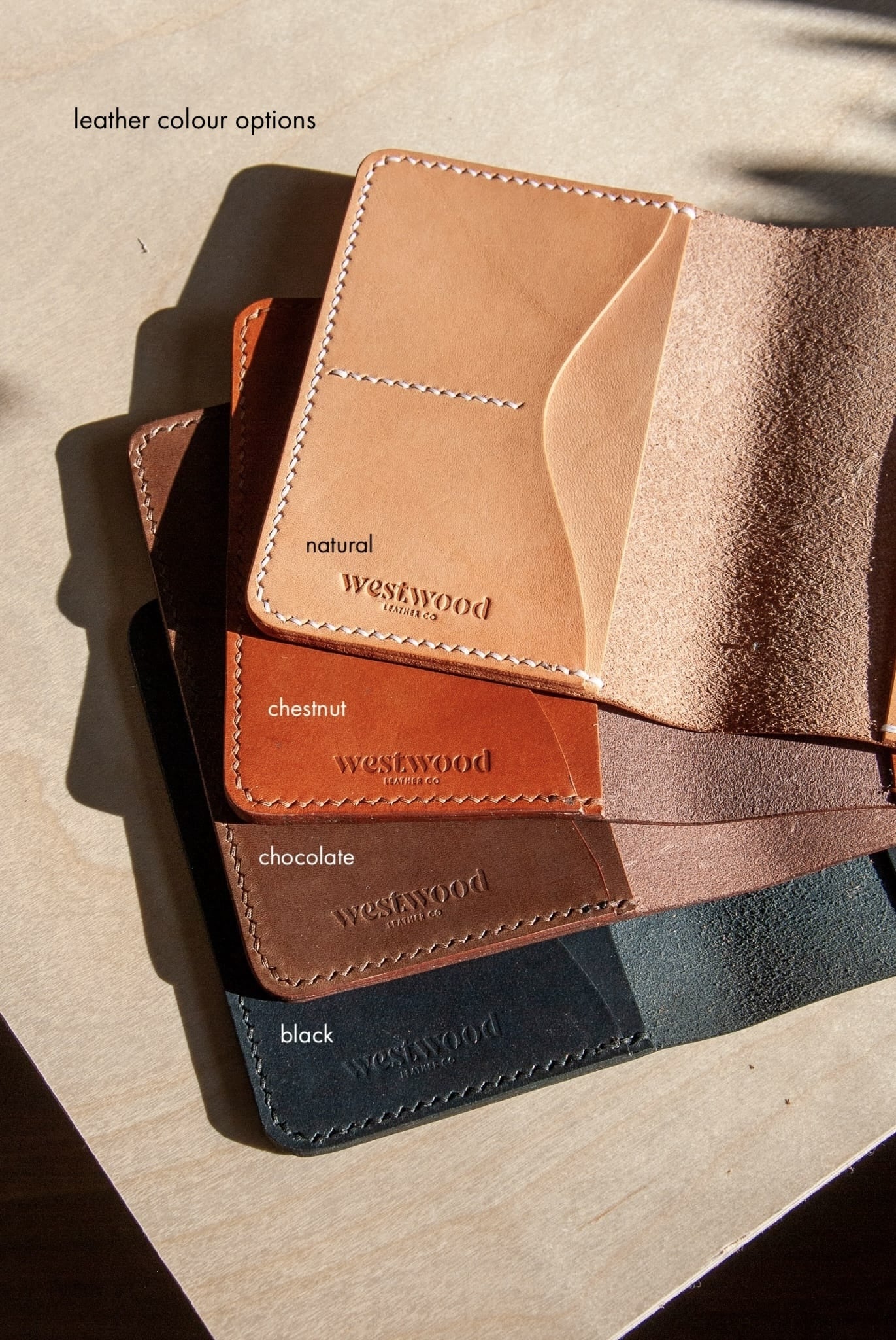 Stack of leather card holders in various colors on a textured surface