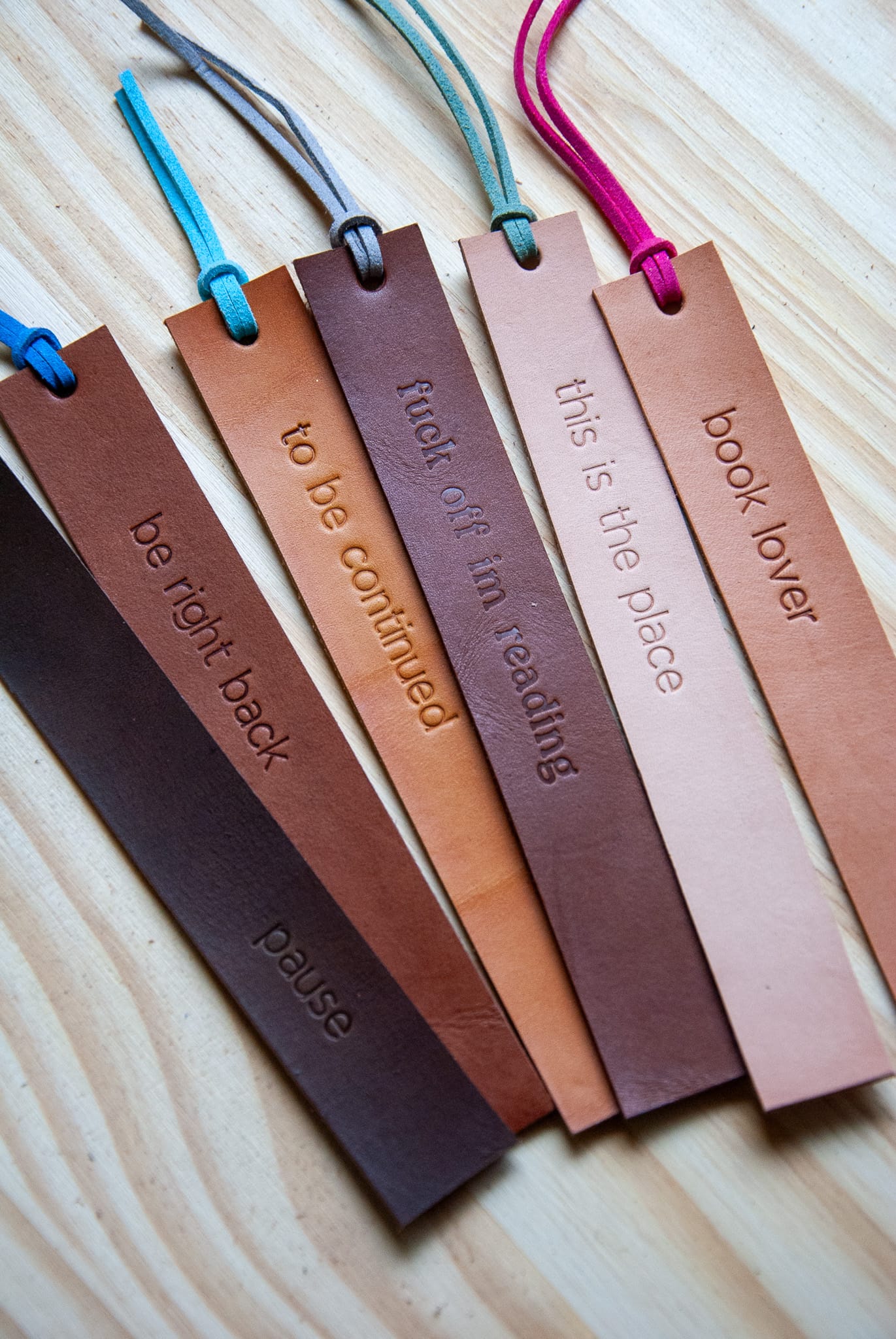 Set of leather bookmarks with embossed text on a wooden surface