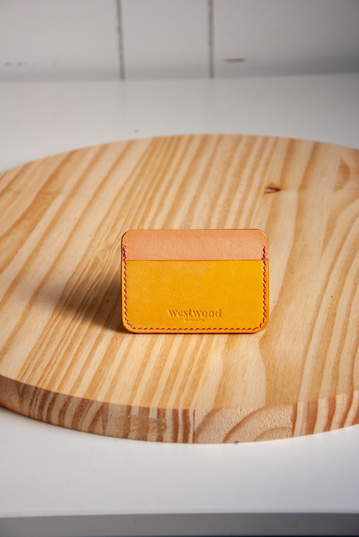 Yellow leather cardholder with 'westwood' branding on a wooden surface