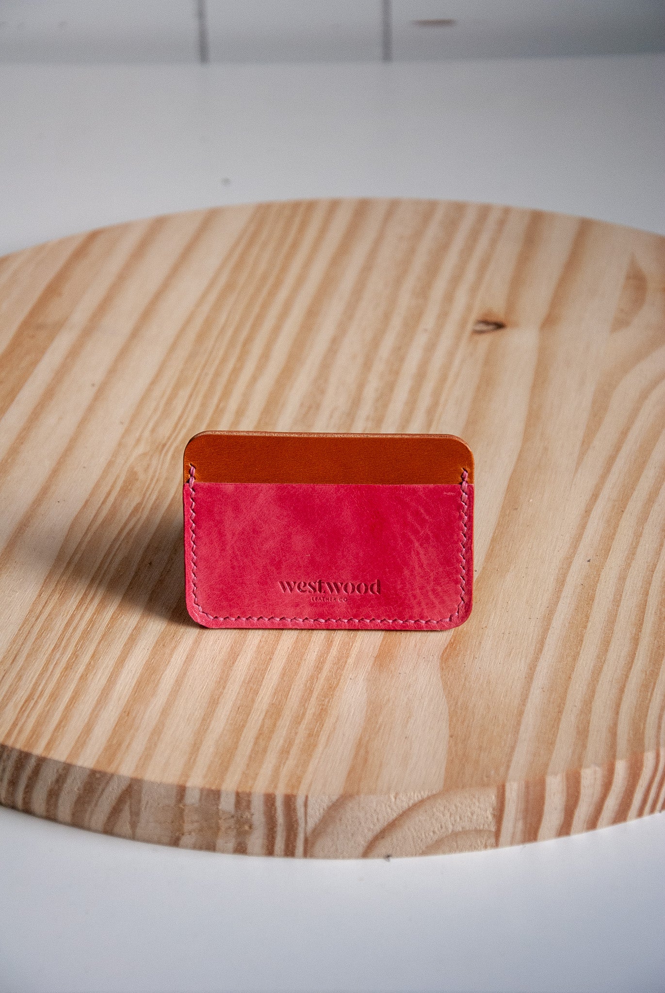 Pink leather cardholder on a wooden surface