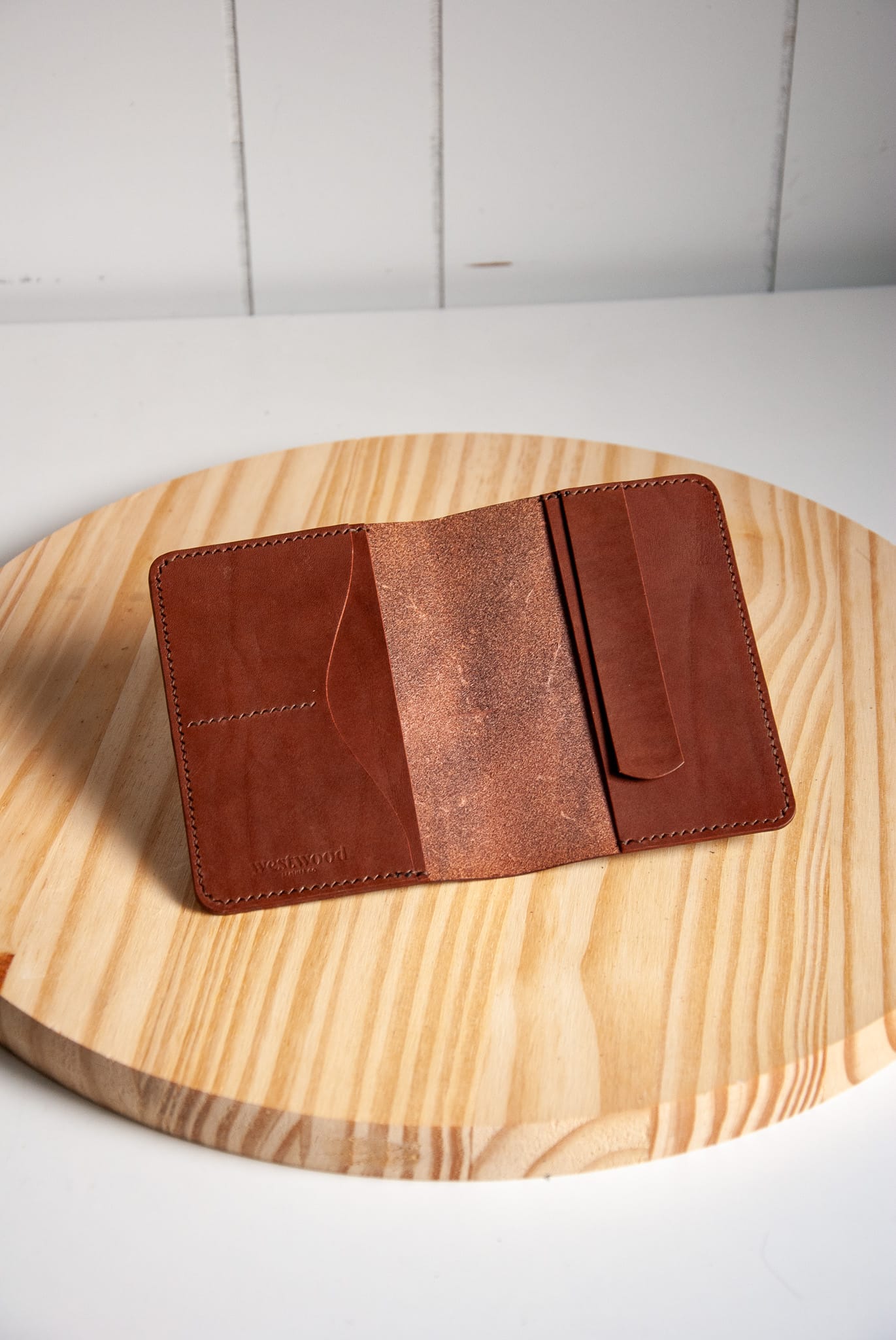Brown leather wallet on a wooden surface with a white background