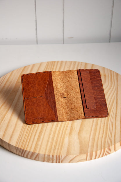 Brown leather wallet on a wooden surface with a white background